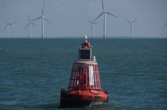 Close-up of buoy with wind farms in background